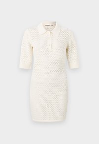 Robe polo en tricot de couleur crème avec des manches courtes, présentant un tissage texturé en maille ouverte et une patte de boutonnage à trois boutons. Col lisse et design ajusté.