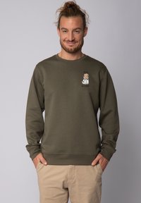 Olijfgroene trui van zachte stof, met een kleine afbeelding van een hond in een labjas en de tekst "Vertrouw me, ik ben een arts."