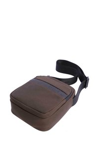 Bolso cruzado compacto de tela marrón con correa ajustable negra y sutil logo grabado en el bolsillo delantero.