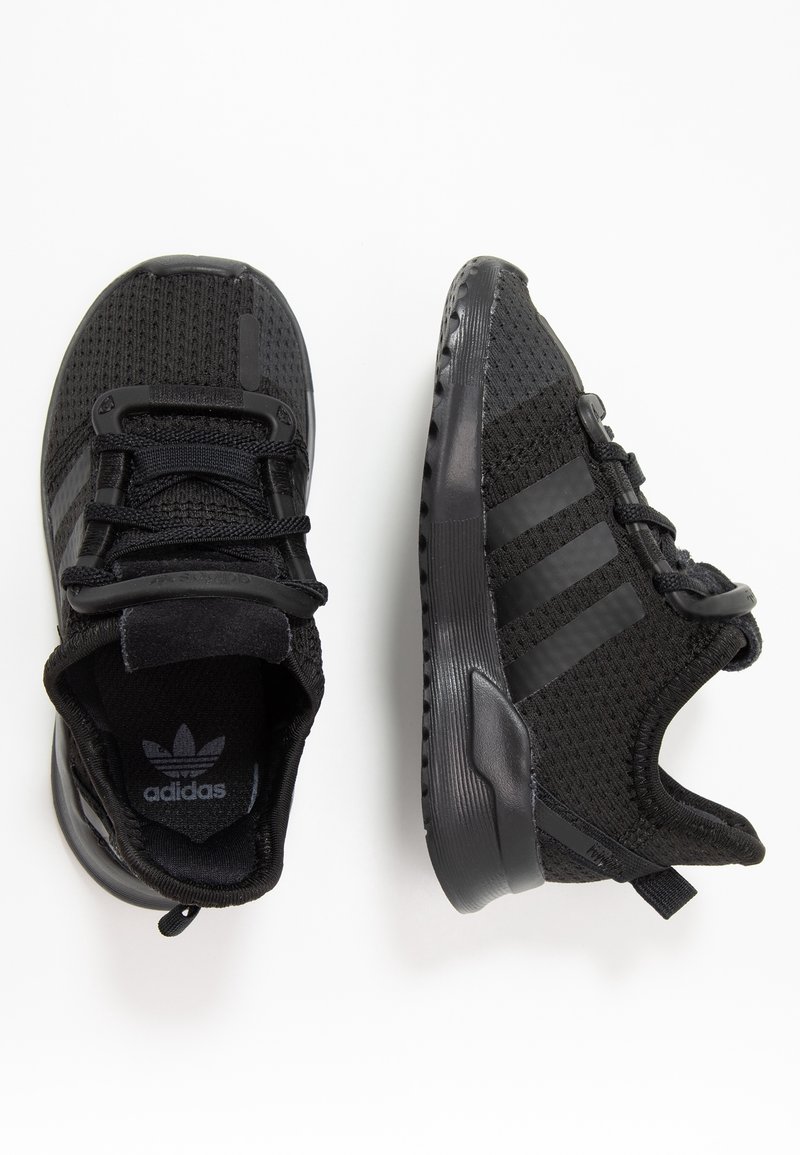 Svarta träningsskor med mesh-överdel, texturerade detaljer och ett mönster med tre ränder. Har en vadderad krage och gummisula för grepp.