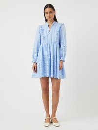 Rochie bleu deschis cu un guler volan, mâneci lungi și modele tăiate intricate pe margine. Pur tată cu pantofi de culoare deschisă.