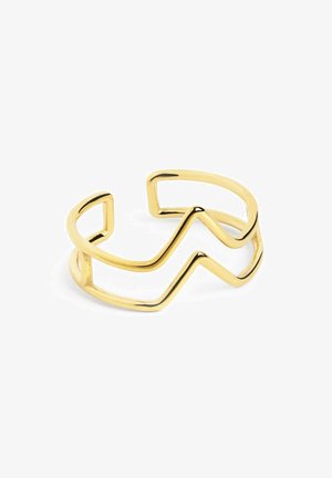 Bracelet en métal doré avec un design en zigzag et des extrémités ouvertes. La surface est lisse et réfléchissante, mettant en avant une esthétique minimaliste.