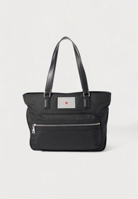 Black tote bag made of textured fabric features dual leather handles, a front zip pocket, and a silver logo plaque on the front.