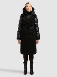 Fekete, két anyagból álló kabát párnázott felsőrészzel és gyapjúszerű alsó résszel, övvel, túlméretezett gallérral és hosszú ujjakkal.