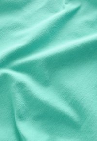 Katoenen stof in een zachte mintgroene kleur, met een gladde textuur en subtiele kreukels en plooien door het oppervlak.