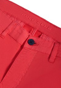 Röda bomullsshorts med en slät yta, försedda med en knappstängning märkt "POLO CLUB" och sydda bältesöglor i matchande färg.