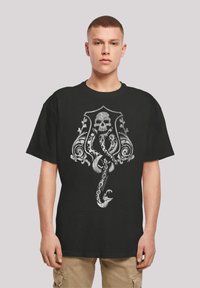 Black cotton t-shirt featuring a detailed silver graphic of a skull entwined with ornate designs and a serpent. Short sleeves and relaxed fit.