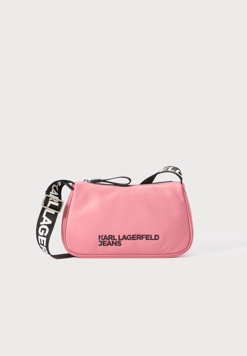Rozā sintētiskā crossbody soma ar rāvējslēdzēja aizdari, ar zīmolu apdruku uz siksnas un melniem uzrakstiem. Gluda tekstūra un taisnstūra forma.