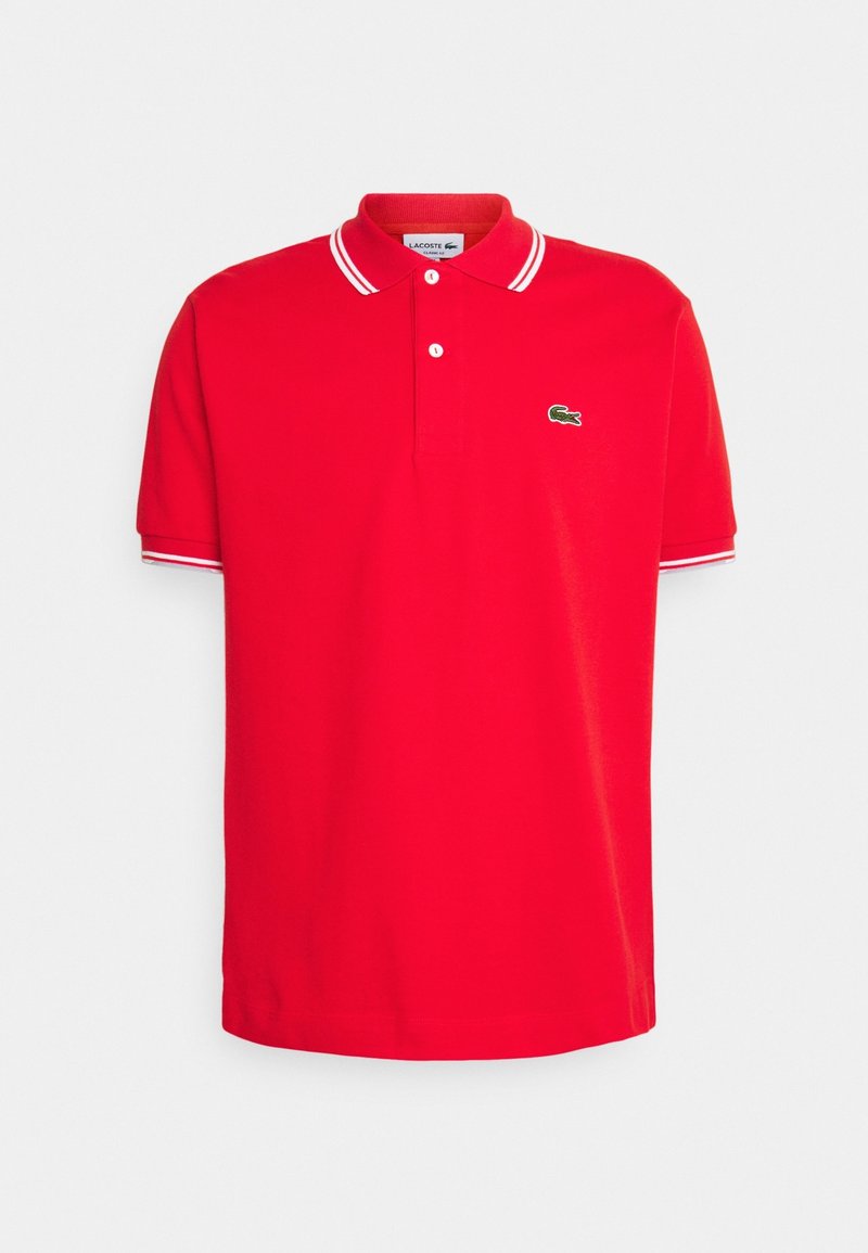 Polo rouge à manches courtes avec col blanc et bandes sur les manches, deux boutons et un petit logo crocodile vert sur la poitrine.