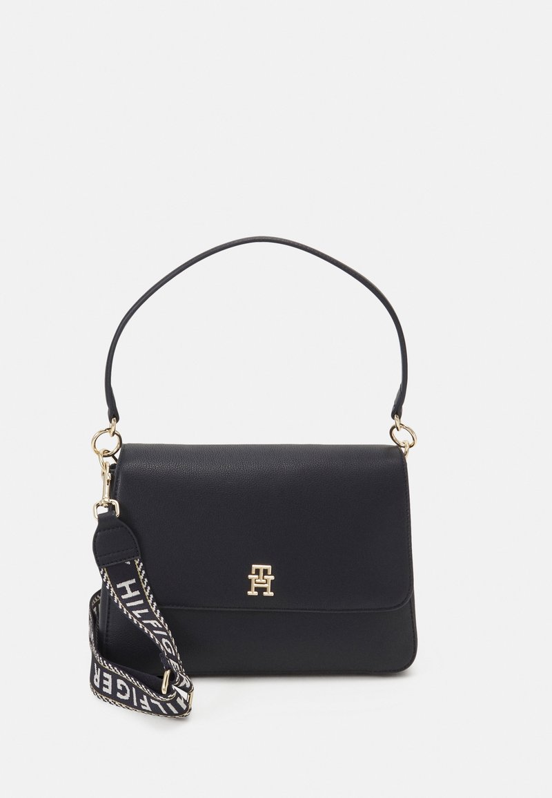 Sac à bandoulière en cuir noir avec logo doré sur le rabat avant et sangle en tissu noir et blanc amovible avec marquage.