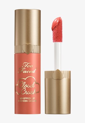 Too Faced Cloud Crush Whipped Lip & Cheek Farbe in einer korallenfarbenen Tube mit goldenen Akzenten; verfügt über einen weichen Applikator mit einer abgerundeten Spitze.