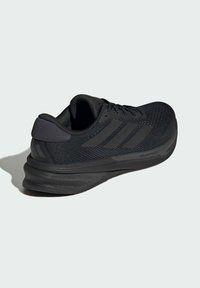 Scarpa sportiva nera con una tomaia in rete testurizzata, detail del logo tridimensionale e una suola in gomma spessa per ammortizzazione e supporto.