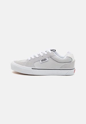 Grå semsket lavtopp sneakers med hvite snører, hvit såle og en svart og hvit logoetikett på siden. Har subtile detaljer og en glatt tekstur.
