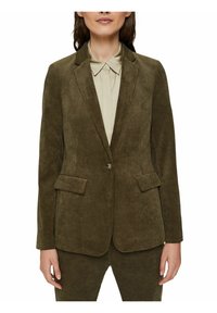 Zielona kordrowa marynarka z klapami, z przodem zapinanym na guziki oraz dwiema naszytymi kieszeniami. Połączona z jasnym kolorem koszuli.