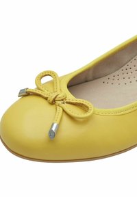 Geel lederen ballerina met een ronde neus, voorzien van een strikaccent en een zilveren hardwaredetail, geplaatst op een lichtgekleurde zool.