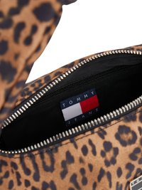 Torba s uzorkom leopardove kože, koja ima glatku teksturu, dva odjeljka sa zatvaračem i markiranu oznaku unutar s plavim, bijelim i crvenim akcentima.