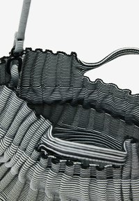 Gestreifte Stofftasche mit einer gerafften Oberseite, die ein schwarz-weißes Wellenmuster zeigt. Das Material ist leicht und flexibel mit verstellbaren Trägern.