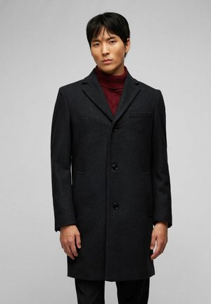 Abrigo de lana gris oscuro con un corte ajustado, diseño de un solo botón, solapas de muesca y un bolsillo en el pecho. Botones negros notables realzan los detalles.