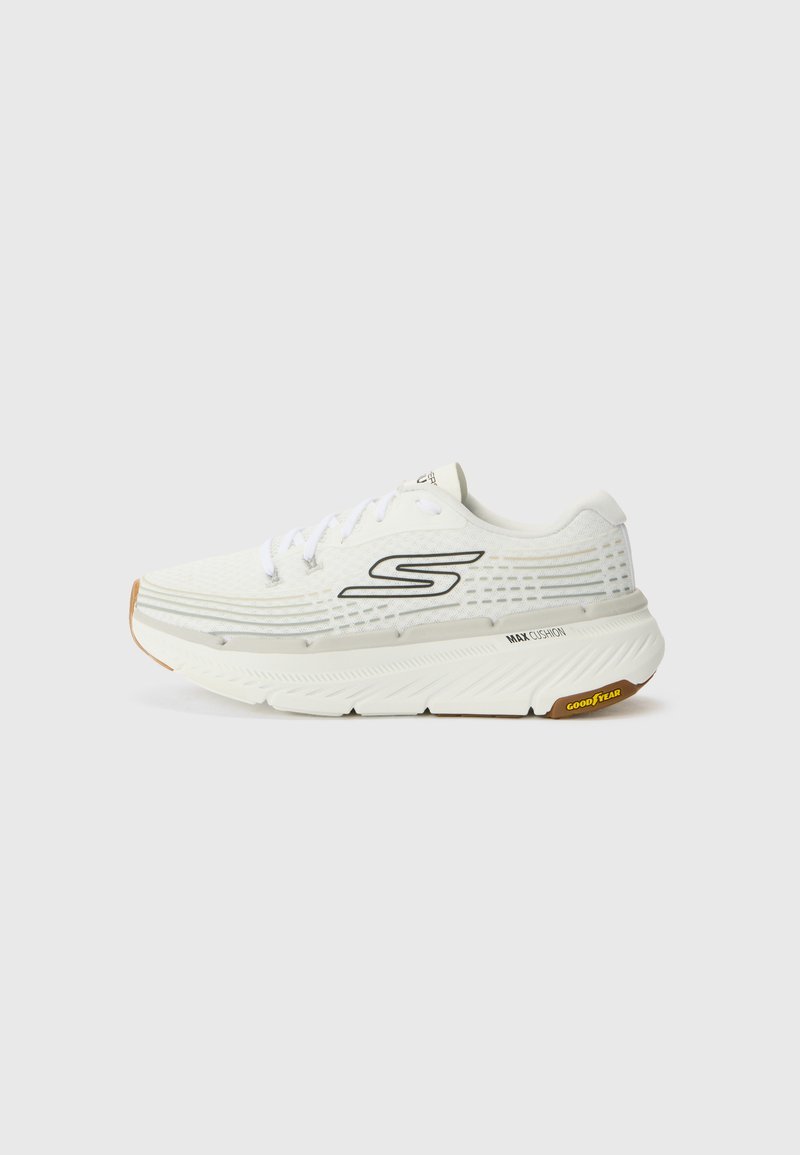 Zapato deportivo blanco con parte superior de malla texturizada, acentos negros, suela gruesa acolchada y suela de goma de color goma. Presenta cordones y detalles del logo.
