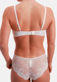 Witte kanten lingerie set met een beha met verstelbare bandjes en een haaksluiting, gecombineerd met slips met een gegolfde rand. Textuurpatroon zichtbaar.