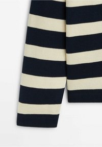 Manche d'un pull tricoté avec de larges rayures horizontales bleu marine et blanc cassé sur un fond blanc.