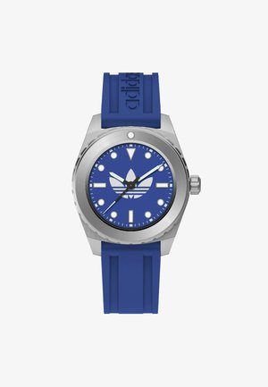 Niebieski zegarek na gumowym pasku ze stalową kopertą, niebieską tarczą, białymi znacznikami godzin oraz logo umieszczonym na środku. Srebrny detal przy koronce.