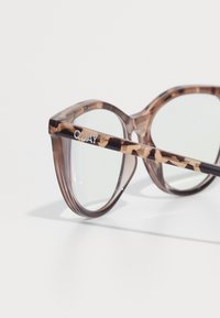 Gafas de sol de gran tamaño con forma de ojo de gato, con una montura de carey translúcido, lentes claros y un logo "QUAY" en plata en la patilla.