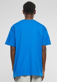 Šviesiai mėlynas, trumpa rankovė t-shirt'as iš medvilnės. Laisvas fasonas su apvalia iškirpte ir tiesia apatine kraštine, pasižymintis lygiu paviršiumi ir vienoda spalva.