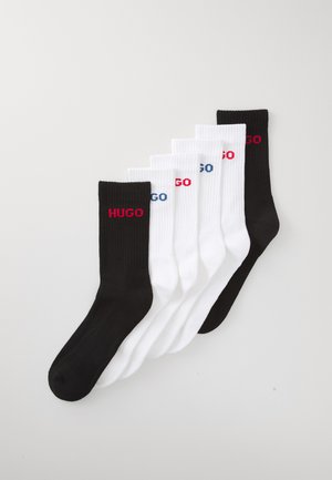 Baumwollsocken in Schwarz und Weiß mit gerippter Textur und dem Logo "HUGO" in Rot und Blau an den Bündchen. Set aus fünf Paaren.