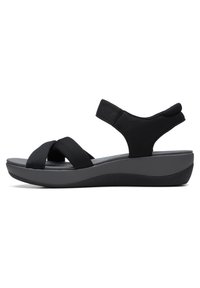 Schwarze Sandalen mit überkreuzten elastischen Riemen und einer gepolsterten grauen Sohle. Sie verfügen über einen Wedge-Absatz und einen gepolsterten Knöchelriemen für Unterstützung.