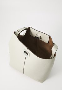Biała skórzana torebka z prążkowaną teksturą, brązowe zamszowe wnętrze, srebrne akcenty metalowe oraz kontrastujący ciemny szew wzdłuż boku.