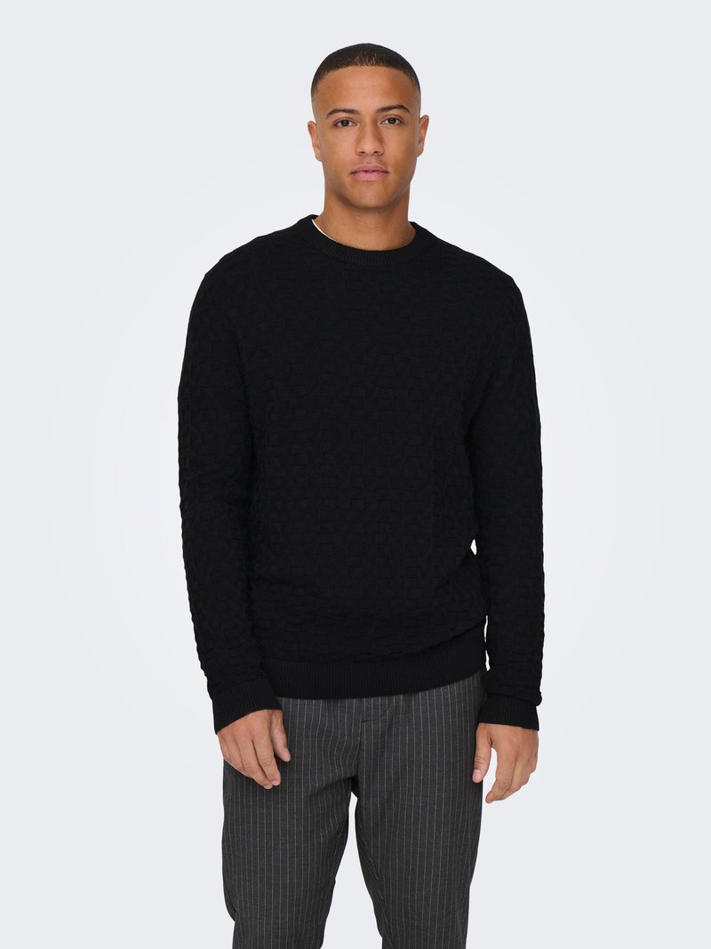 Black knit sweater with a textured pattern, round neckline, and ribbed cuffs and hem. Worn with gray pinstriped trousers.