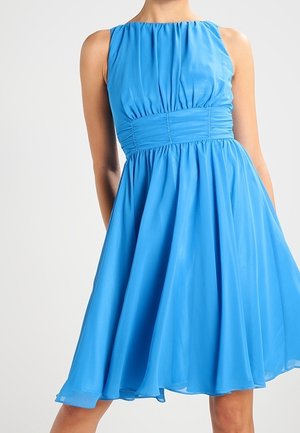 Bezrekawowa, jaskrawo niebieska sukienka do kolan z marszczonym dekoltem i szerokim marszczonym paskiem w talii, na stojącej osobie.