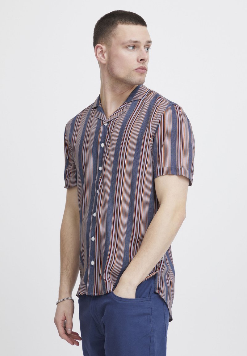 Camicia a maniche corte con bottoni, a righe verticali nei colori navy, rosso e crema. Tessuto leggero, colletto con spacco e vestibilità comoda.