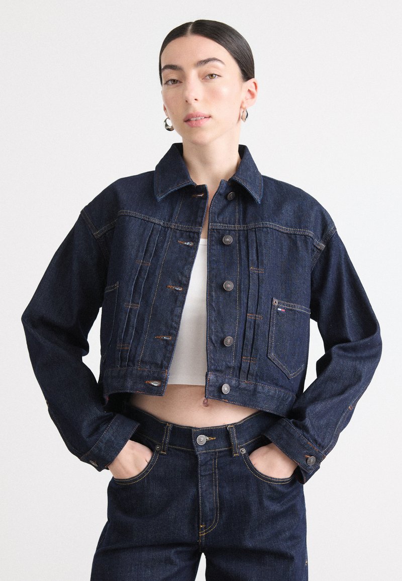 Kuttet denimjakke i mørkeblå med oransje sømmer, med knappefront, to lommer og klassisk krage.