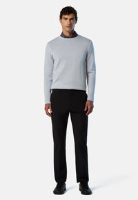 Hellgrauer, langärmeliger Pullover mit Rundhalsausschnitt, kombiniert mit schwarzen Hosen und schwarzen Sneakers. Glatter Stoff, lässige Passform.