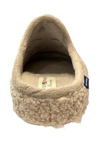 Beige vilten slipper met een zachte, gestructureerde buitenkant, ronde neus en een pluche voering. Heeft een klein merkembleem aan de zijkant.