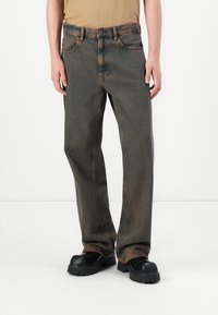 Donkergrijze denim jeans met een rechte snit, voorzien van oranje stiksels en een knoopsluiting. Draagt ze met zwart met een dikke zool.