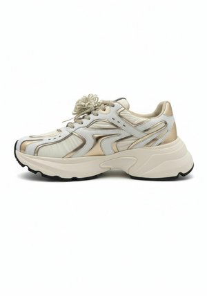 Stevige beige en witte sneaker met metallic gouden accenten, dikke gevoerde zool en veterluiting, gezien vanaf de zijkant.