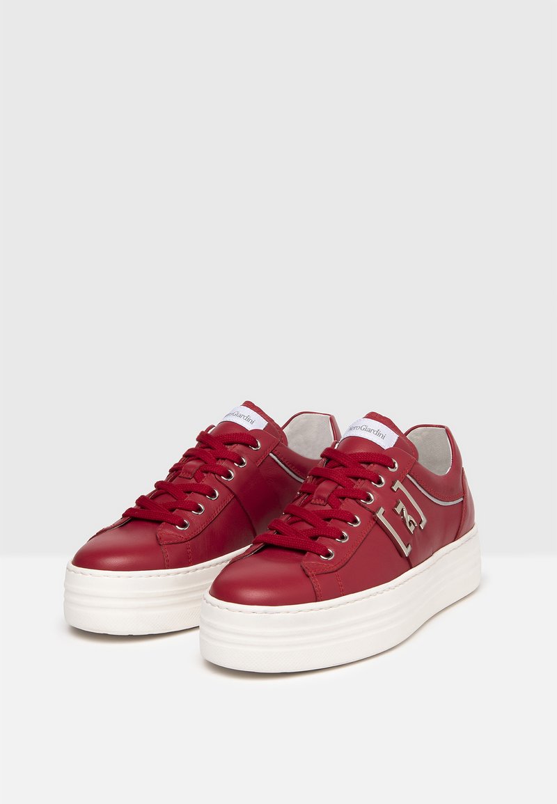 Sneaker in pelle rossa con punta tonda, suola piatta in gomma bianca e design con lacci. Presenta accentature con logo e cuciture a contrasto.