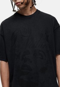 T-shirt nera oversize con stampa grafica che presenta il testo "Good for Nothing" e un design di un volto sottile. Realizzata in morbido cotone.