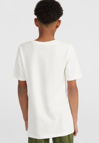 Camiseta de algodón blanca con mangas cortas y un cuello redondo clásico. Textura suave, corte relajado, sin marcas ni patrones visibles.