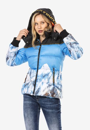 Blauer Daunenjacke mit Bergdruck im unteren Bereich, schwarzer Kapuze, gerippten Bündchen und kontrastierenden Reißverschlüssen. Logoband um den Kragen.