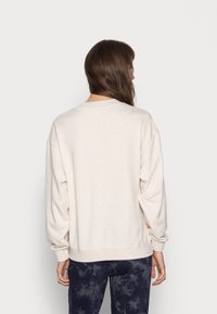 Sudadera oversize de color beige claro con escote redondo y hombros caídos, con mangas largas y dobladillo y puños acanalados.