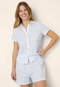 Ljust blå bomullskort pyjamas med en knäppning skjorta med krage och matchande shorts med elastisk midja, prydda med ett subtilt blommönster.