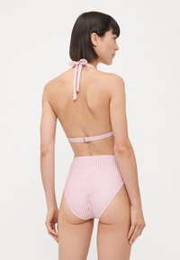 Top bikini a righe rosa con laccetto regolabile al collo e chiusura sul retro, abbinato a un pantalone alto con righe verticali. Texture liscia.