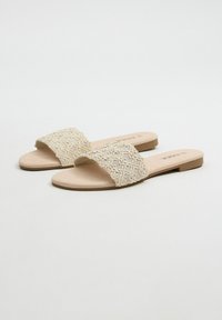 Sandalias deslizantes beige con una parte superior de tela trenzada, que cuentan con una correa texturizada y una suela de goma plana para mayor comodidad y facilidad de uso.