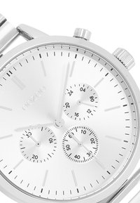 Montre chronographe argentée avec un boîtier en acier inoxydable brossé. Elle dispose de trois sous-cadrans, de marqueurs d'heure minimalistes et d'un cadran texturé.