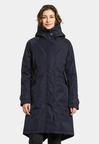 Marineblå lång kappa med hög krage, framdragkedja, två sidofickor och knappdetaljer på ärmarna, tillverkad av vattentätt material.