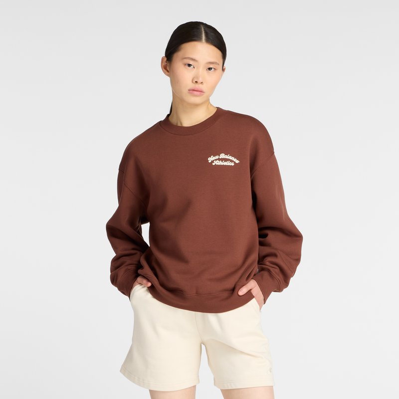 Brauner Sweatshirt mit lockerer Passform, geripptem Kragen und cremefarbener "New Balance Athletics" Stickerei. Kombiniert mit hellen Shorts.